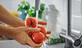 Fresh fruits and vegetables being washed under cold running water to remove dirt, bacteria, and pesticides.