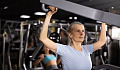 Woman uses weights at the gym to build strength and prevent muscle loss.